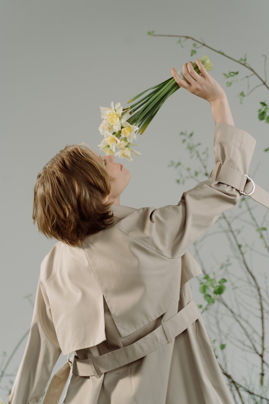 A Woman in Trench Coat Smelling Flowers